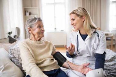 A health visitor measuring a blood pressure of a senior woman at home.