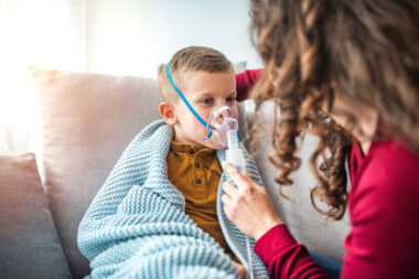Woman with son doing inhalation with nebulizer at home. Causian