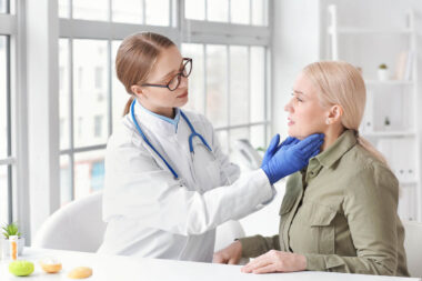 Doctor examining senior woman with thyroid gland problem in clin