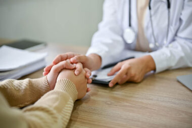 Close up view of doctor touching patient hand, showing empty and kindness.