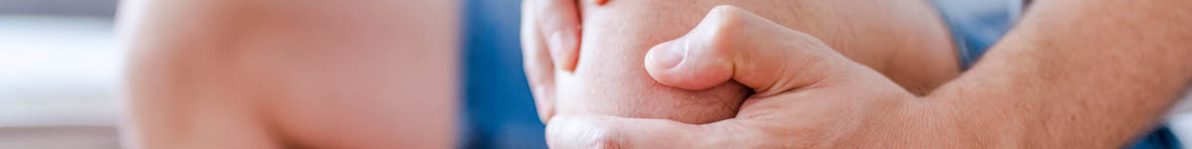 Man suffering from knee pain sitting sofa