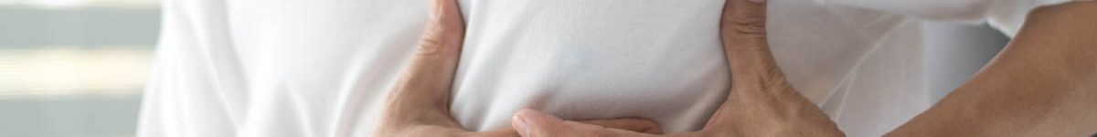 Man’s hands on his chest in white shirt with red spot as sufferi