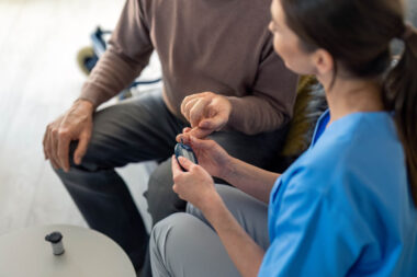 Unrecognizable female nurse measuring blood sugar during home vi