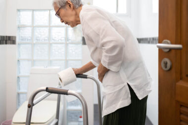 Senior woman with diarrhea holding tissue roll near a toilet bow